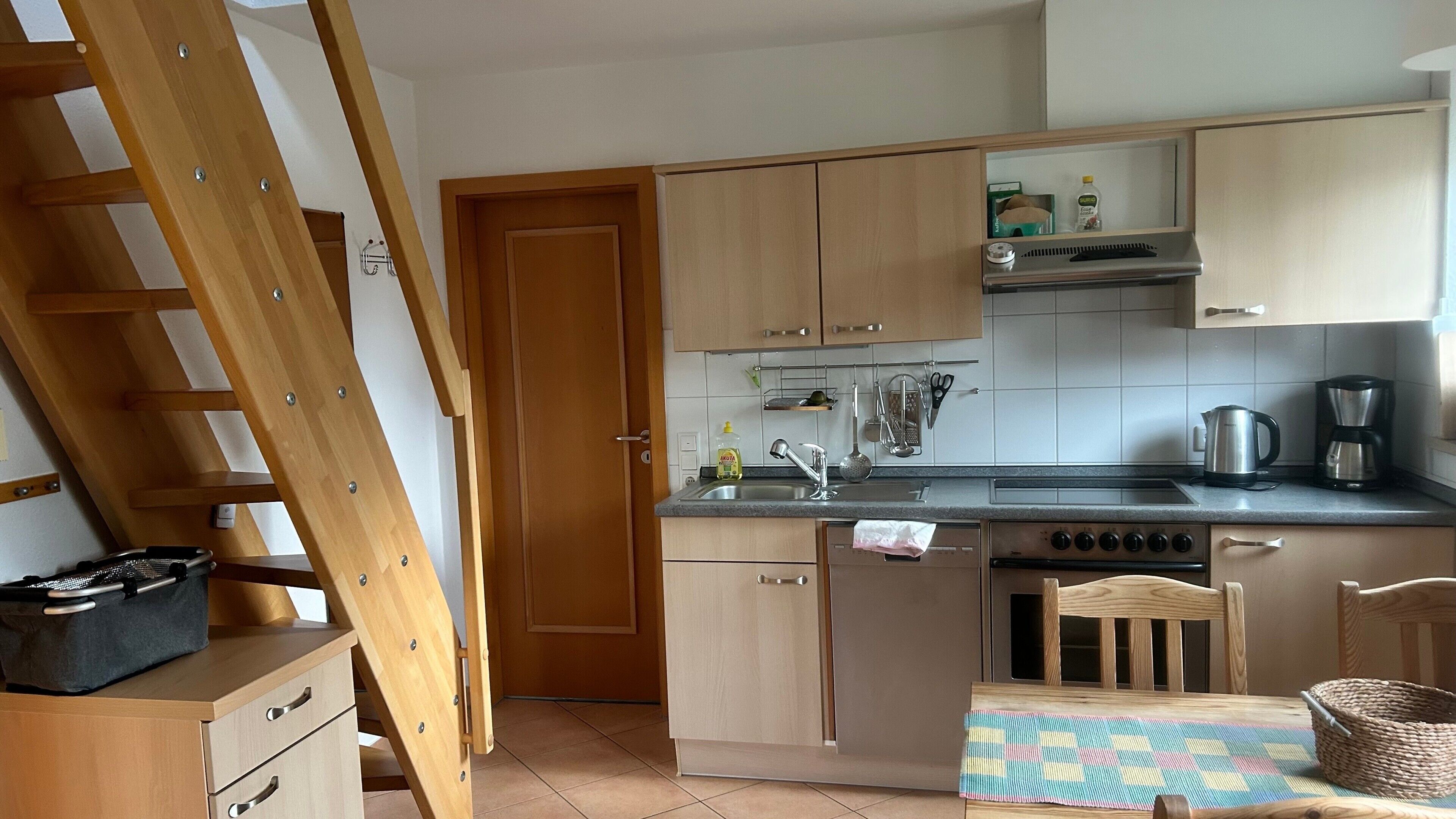 Una cocina con armarios de madera, estufa, fregadero y comedor con mesa y sillas.