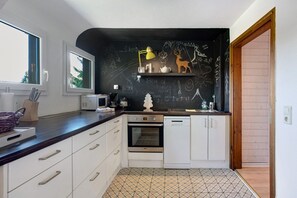 A kitchen with white cabinets, a black backsplash, a window, and a door leading to another room. - Apartment 'Zipfelmütze' with Shared Garden, Balcony, Sauna and Wi-Fi (Feldberg)