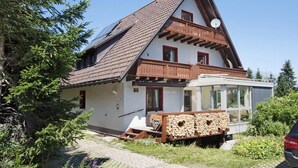 A two-story chalet with a sloped roof, wooden balcony, and a satellite dish. - Apartment 'Zipfelmütze' with Shared Garden, Balcony, Sauna and Wi-Fi (Feldberg)