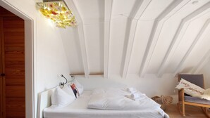 Une chambre à coucher avec un lit, une chaise et un luminaire fixé au mur.