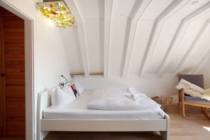 A bedroom with a bed, a chair, and a wall-mounted light fixture. - Apartment 'Spatzennest' with Shared Garden, Balcony and Wi-Fi (Feldberg)