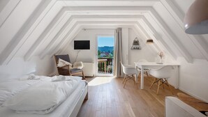Une chambre avec un lit, un bureau et une chaise, un téléviseur fixé au mur et une vue sur l’extérieur.