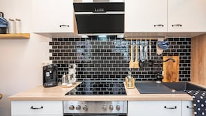 A modern kitchen with a black tiled backsplash, stainless steel appliances, and wooden cabinets. - Half-Timbered Apartment 'Fachwerk' with Wi-Fi (Neustadt an der Weinstrasse)