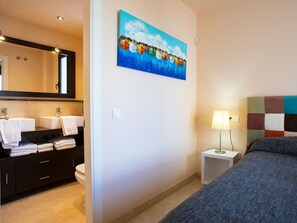 Une chambre d’hôtel avec une salle de bain, un tableau, une lampe de chevet et un lit.