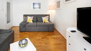 A modern living room with a grey sofa, a white cabinet with a TV, and a lamp. - Characterful Apartment in the Heart of Kassel with Parking Included (Kassel)