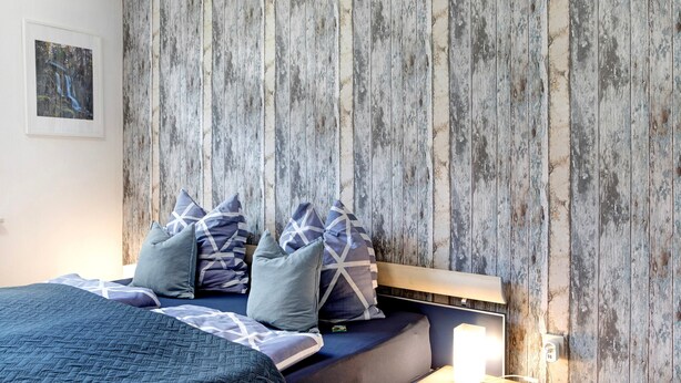 A bed with a headboard, pillows, and a bedside table with a lamp. - Characterful Apartment in the Heart of Kassel with Parking Included (Kassel)