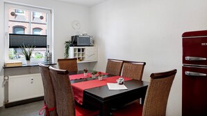 A dining area with a table, chairs, a red tablecloth, a clock, a television, and a red cabinet. - Characterful Apartment in the Heart of Kassel with Parking Included (Kassel)