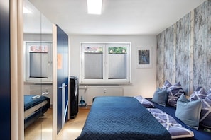 A bedroom with a bed, a wardrobe, a radiator, and a window with blinds. - Characterful Apartment in the Heart of Kassel with Parking Included (Kassel)