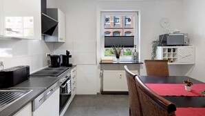 A modern kitchen with a dining area, a view of buildings outside, and a clock on the wall. - Characterful Apartment in the Heart of Kassel with Parking Included (Kassel)