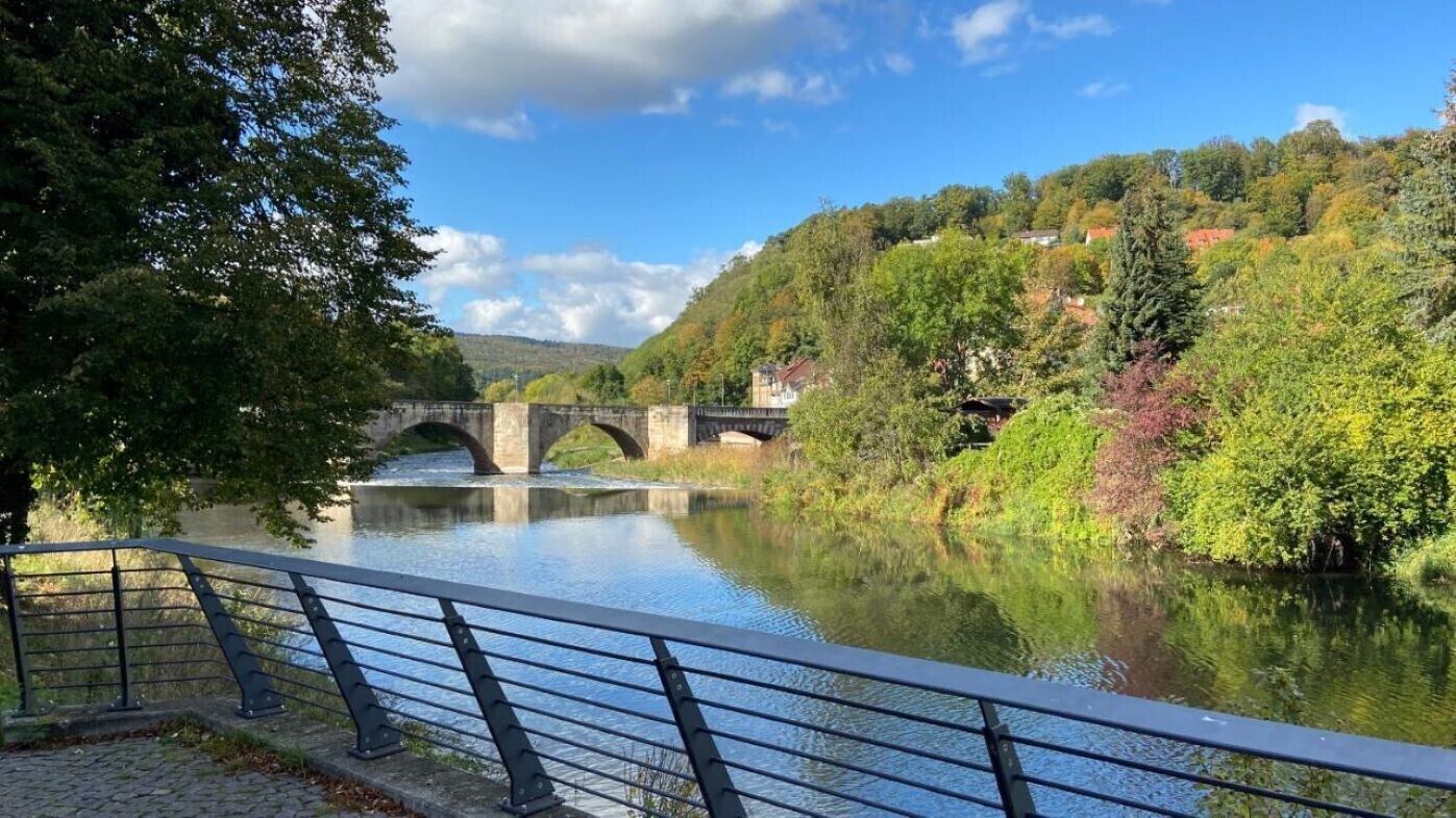 A river with a bridge, surrounded by trees and a clear sky.