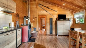 A wooden interior with a kitchen, dining area, and a fireplace. - Chalet 'Pröllerhütte' with Private Terrace and Private Garden (St. Englmar)