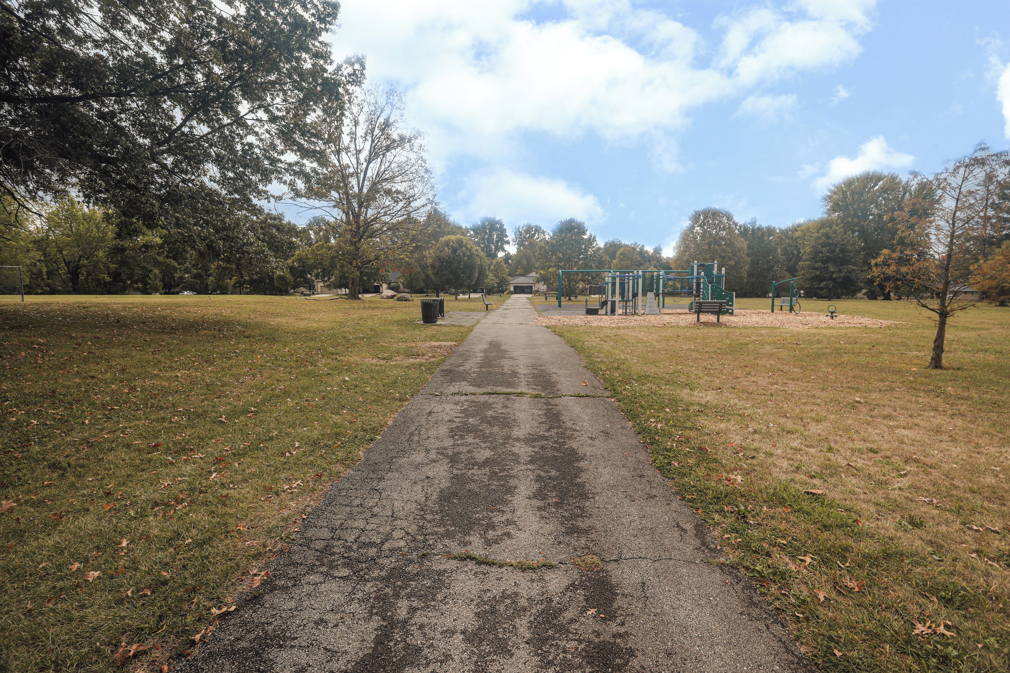 Un sendero en un parque que conduce a juegos infantiles.