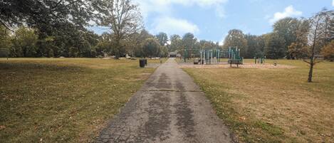 Un sendero en un parque que conduce a juegos infantiles.