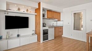 Eine moderne Küche mit weißen Schränken, einem eingebauten Backofen, einer Mikrowelle und einem großen Flachbildfernseher.