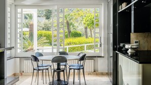 Eine moderne Küche mit Essbereich, großen Fenstern und Blick auf Grünflächen.