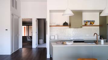 A modern kitchen with a central island, pendant lighting, and a dining area with a wooden table and chairs.