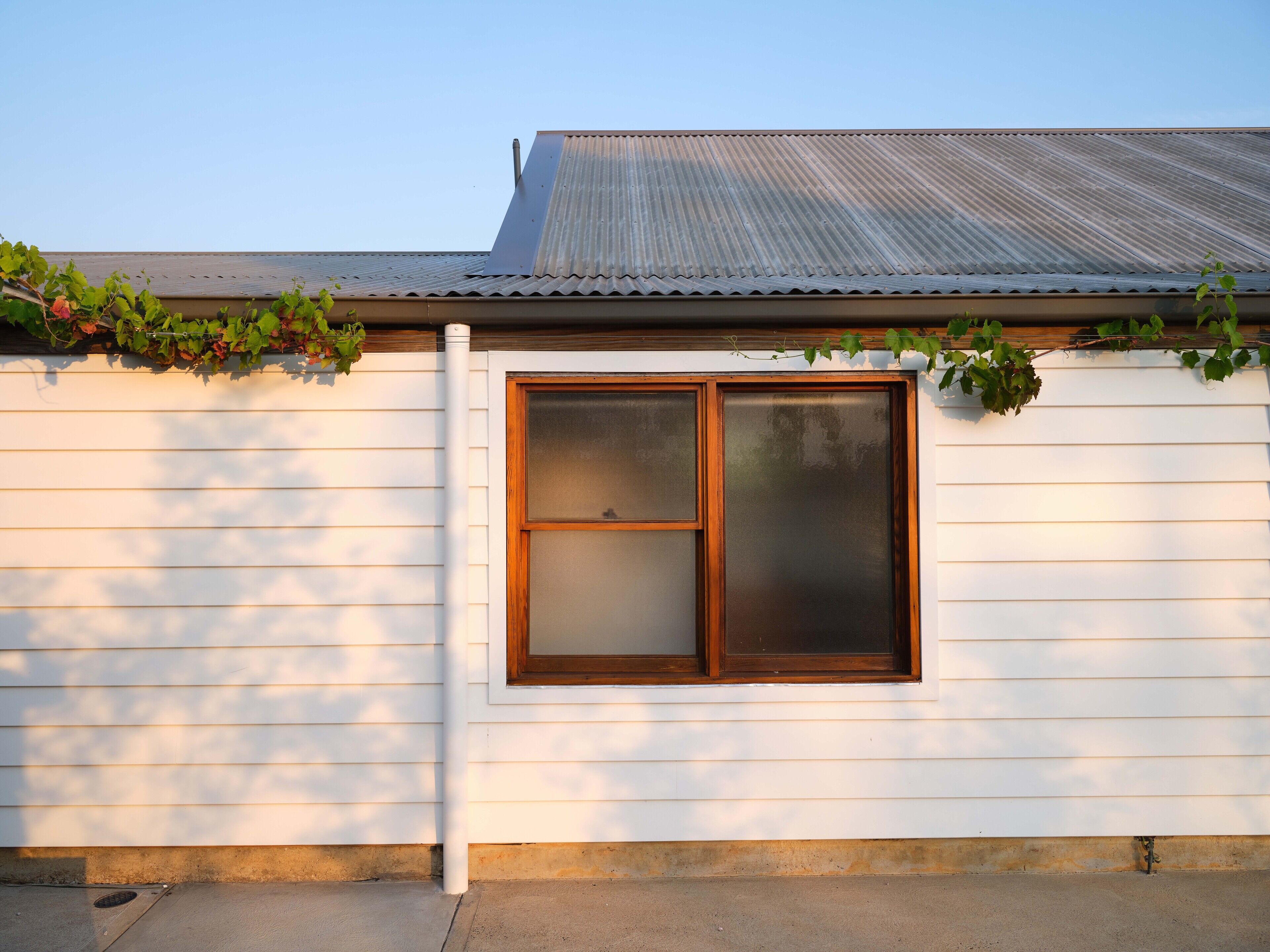 A white building with a window and a metal roof.