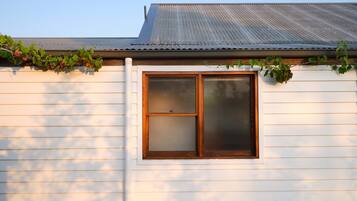 A white building with a window and a metal roof.