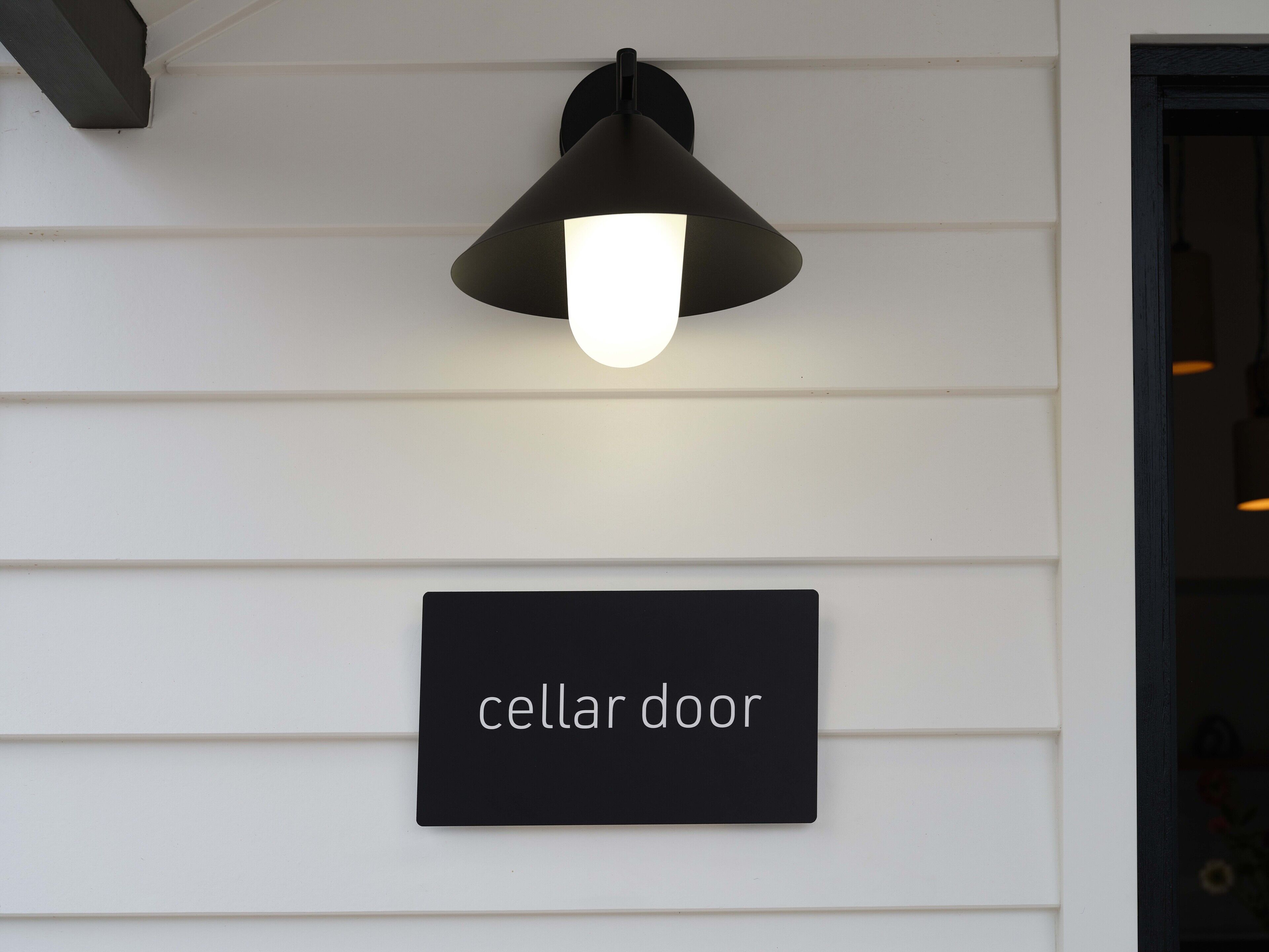 En vægmonteret lampe over et skilt med teksten 'cellar door'.