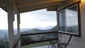 A balcony with a table and chairs, overlooking a mountainous landscape. - Cabin Near Sequoia & Kings Canyon National Parks (Dunlap)