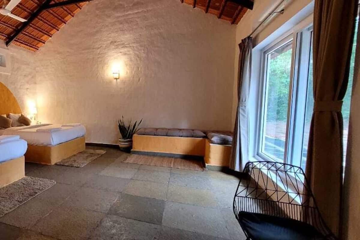 A bedroom with two beds, a seating area, and a large window.