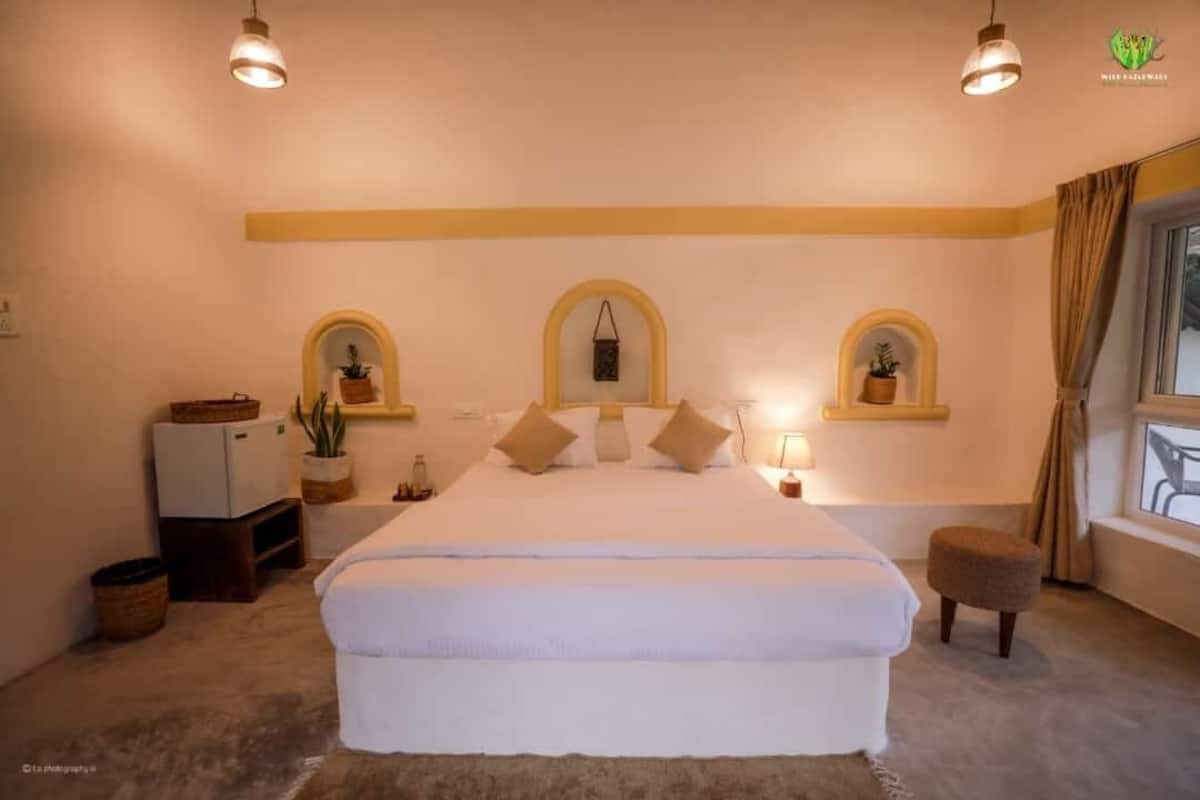 A bedroom with a large bed, two bedside tables, a small stool, and three wall-mounted planters.