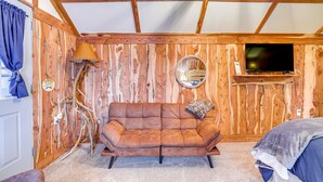 Une pièce chaleureuse avec un mur en bois, un canapé, une lampe et un téléviseur.