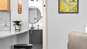 A modern kitchen with a round mirror, a welcome sign, and a framed map on the wall. - Rooftop Hot Tubs I Dogs Welcome I Near DT TC (Traverse City)