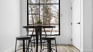 A room with a large window, a table with four stools, and a door. - Rooftop Hot Tubs I Dogs Welcome I Near DT TC (Traverse City)