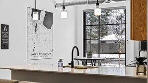 A modern kitchen with a large window, a map on the wall, and a welcome sign. - Rooftop Hot Tubs I Dogs Welcome I Near DT TC (Traverse City)