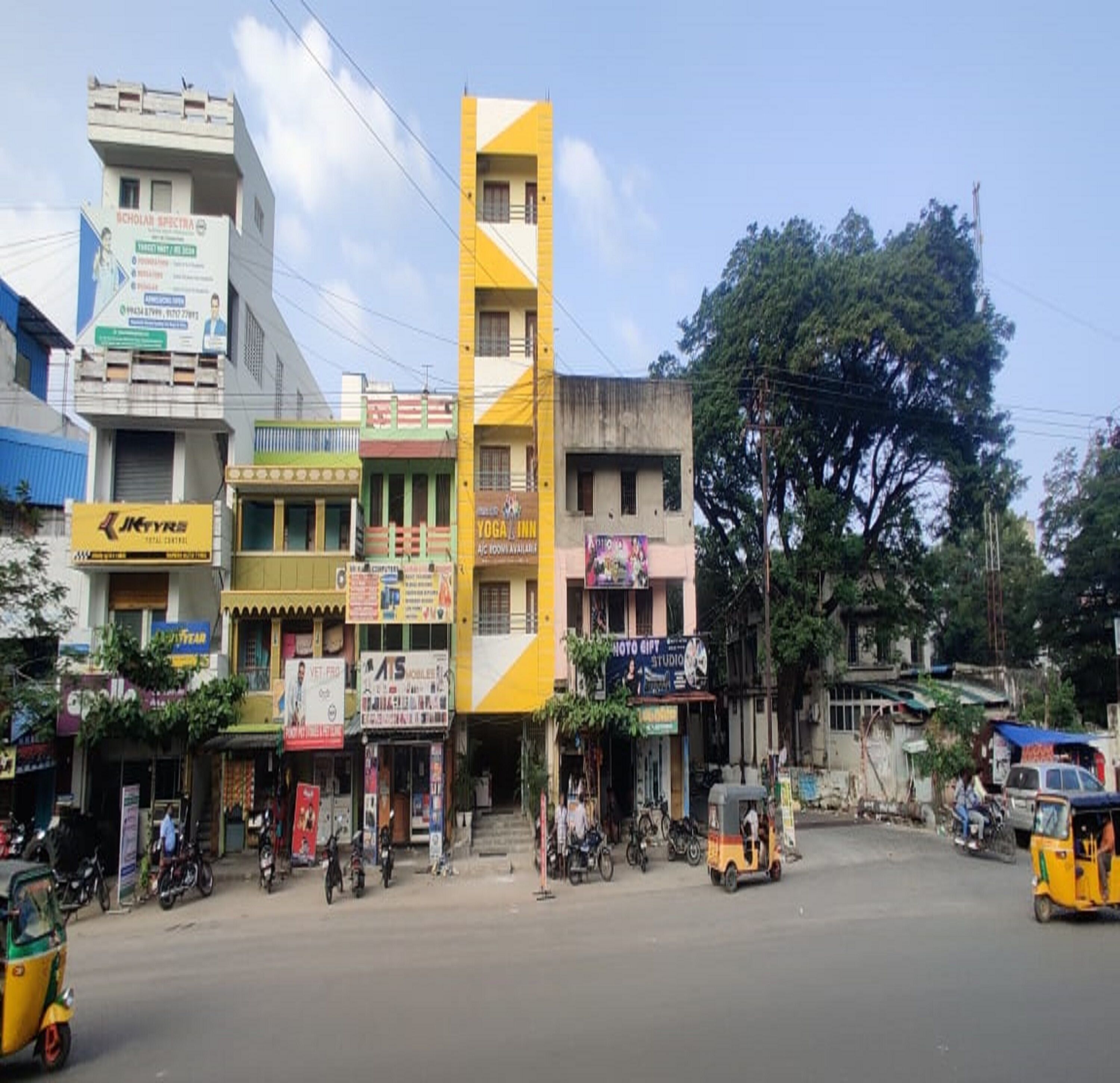 A street with various shops, including a yoga studio and a mobile phone store.