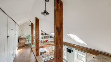 Une pièce de style « loft », avec des poutres en bois apparentes, une lucarne et une vue sur la pièce adjacente.
