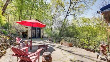 Une terrasse avec des fauteuils Adirondack rouges, un parasol rouge et un foyer extérieur.