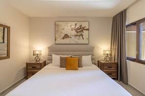A hotel room with a large bed, two bedside tables with lamps, a headboard, and a large abstract painting on the wall. - Stunning Condo in Luxe Resort Azzurro by Bocobay (Noord)