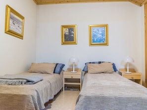 Een kamer met twee bedden, elk met een nachtkastje en een lamp. Twee ingekaderde foto's hangen aan de muur.