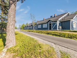 A row of blue houses with a paved road in front.