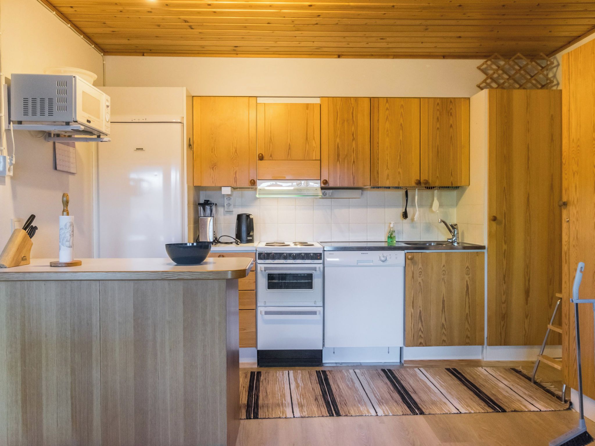 A kitchen with wooden cabinets, a white refrigerator, a stove, and a dishwasher.