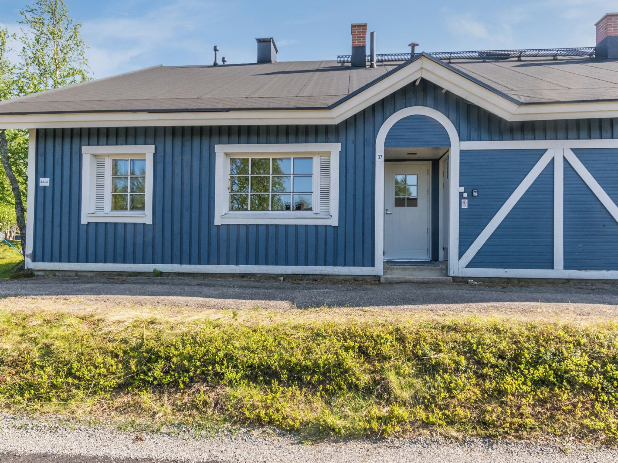 A single-story building with a gabled roof, a front door, and two windows with shutters.
