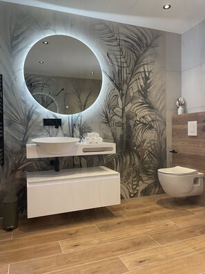 Ein Badezimmer im modernen Design mit rundem Spiegel, Waschbecken in Weiß und Toilette.