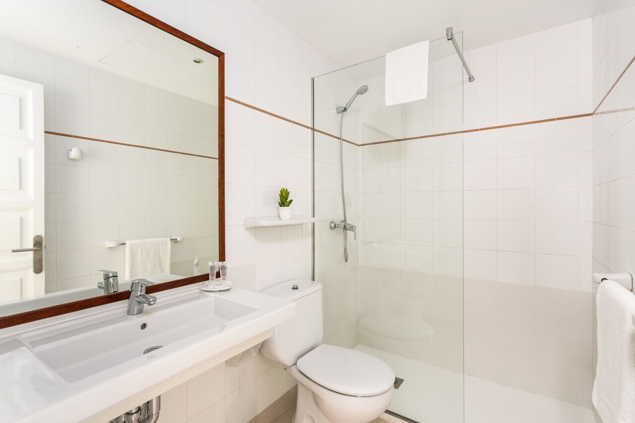 A modern bathroom with a white sink, mirror, and toilet.