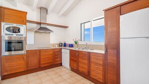 A kitchen with wooden cabinets, a stainless steel oven, a dishwasher, and a window with a view.