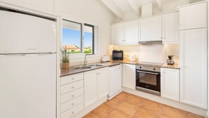 A modern kitchen with white cabinets, a built-in oven, a microwave, and a sink. - Menorca Sur T3, 3 bedroom (Torre Soli Nou)