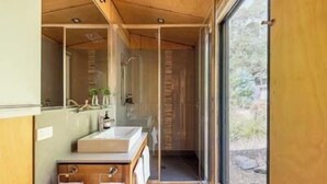 A modern bathroom with a large mirror, a wooden vanity, and a shower area. - Hidden on Huon, exclusive getaway (Police Point)