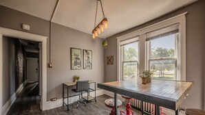 A modern kitchen with a large island, red stools, and a hanging light fixture.
