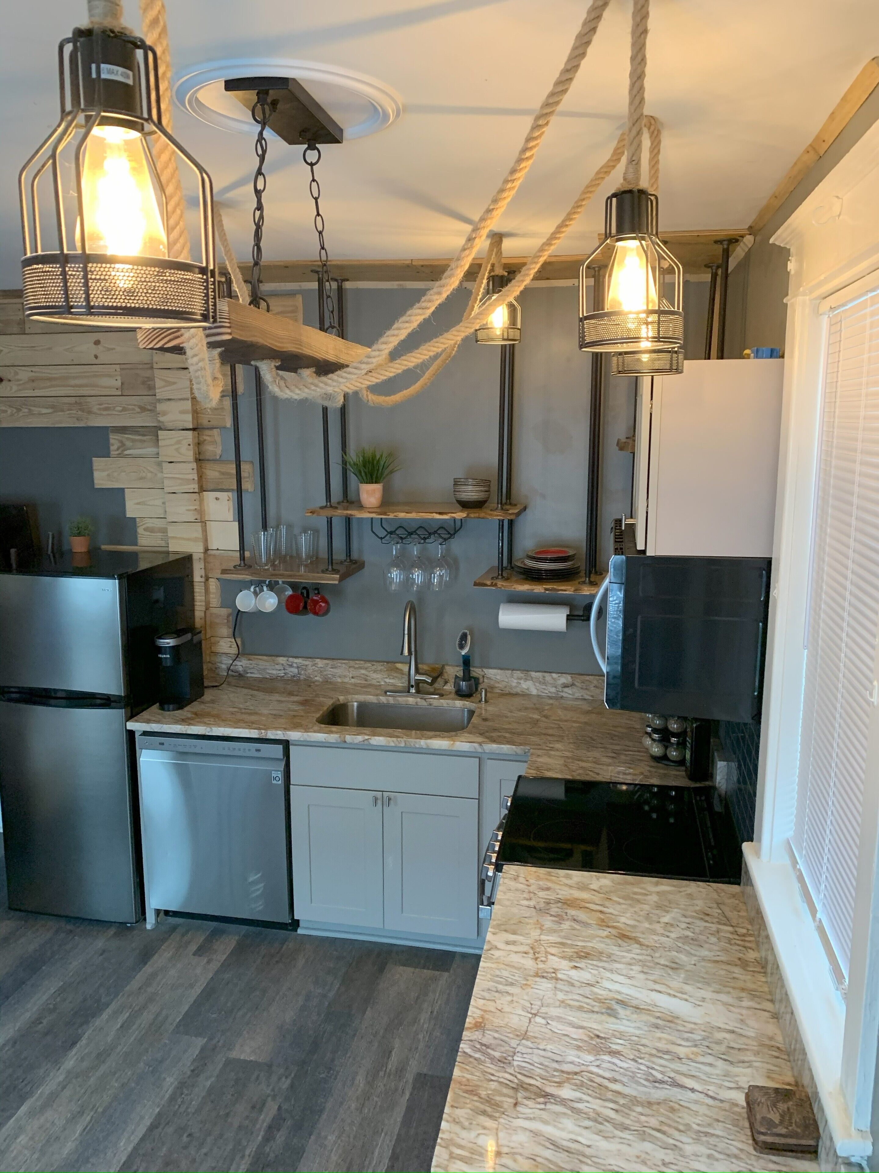 A modern kitchen with a central island, stainless steel appliances, and exposed wooden beams.