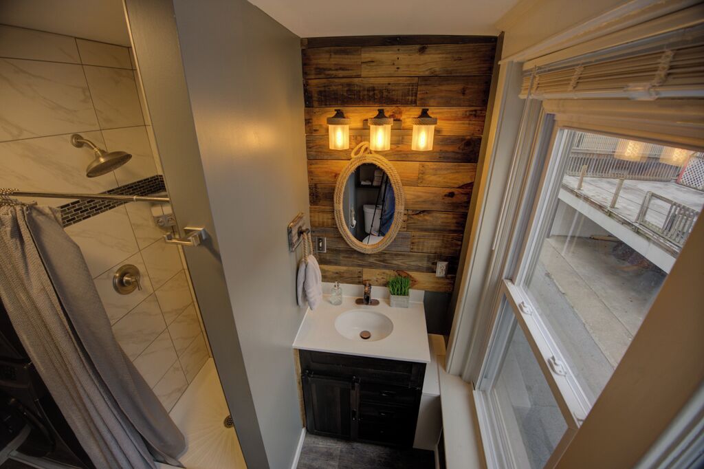 Une salle de bain avec un mur en bois, un lavabo, un miroir et une douche.