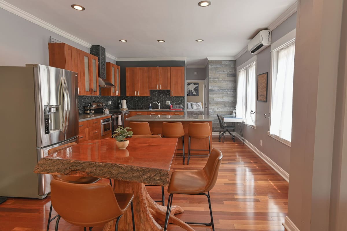 A modern kitchen with a central island, wooden cabinets, and a stainless steel refrigerator.