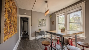A modern kitchen with a wooden table, red stools, and a hanging light fixture. - BurgBnB Riverfront (Harrisburg)