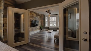A room with a wooden wall, a flat-screen TV, a sofa, and a window with a view. - BurgBnB Riverfront (Harrisburg)