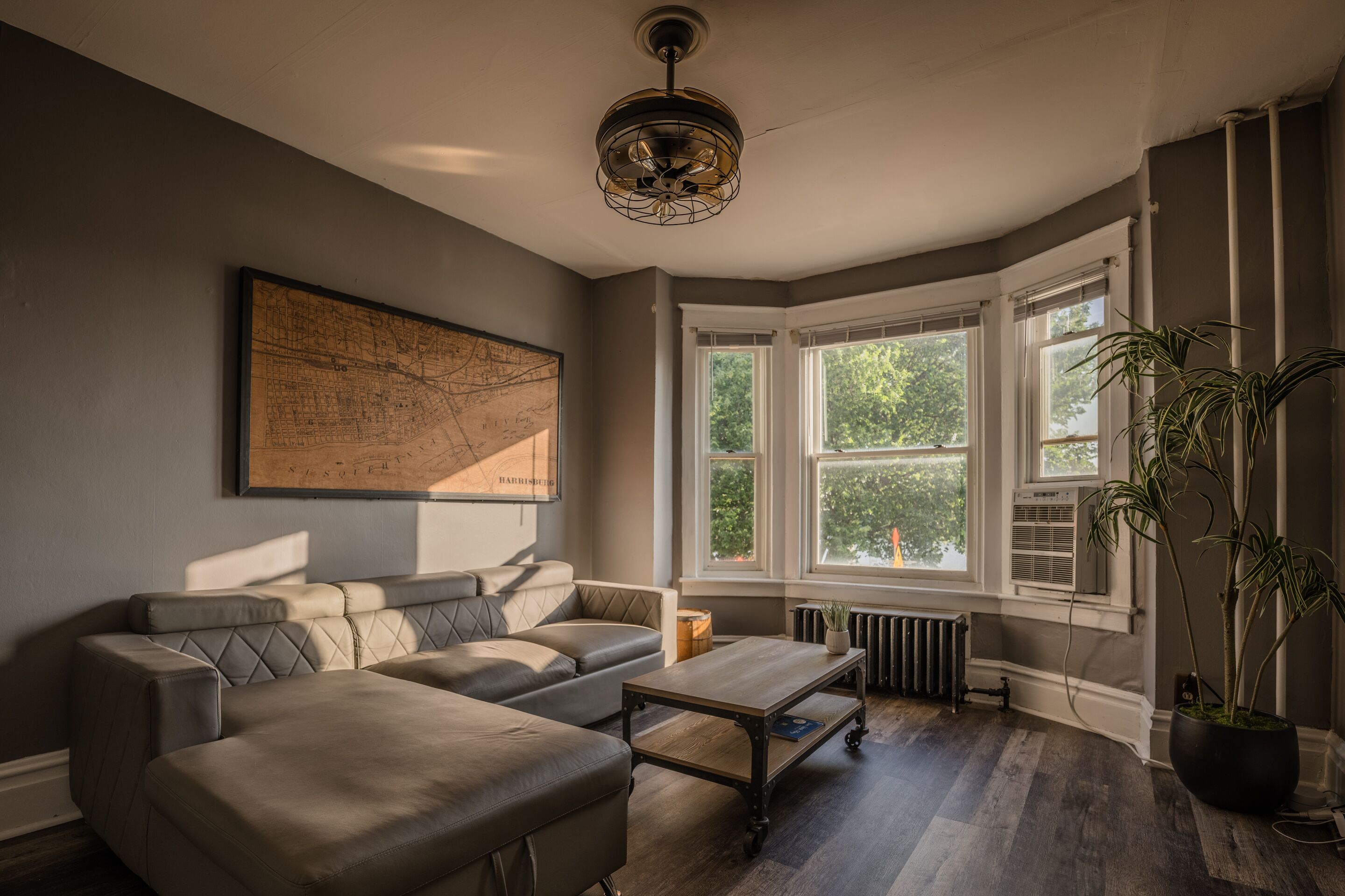 Ein modernes Wohnzimmer mit einer Eckcouch, einem Holztisch und einer großen Karte an der Wand.